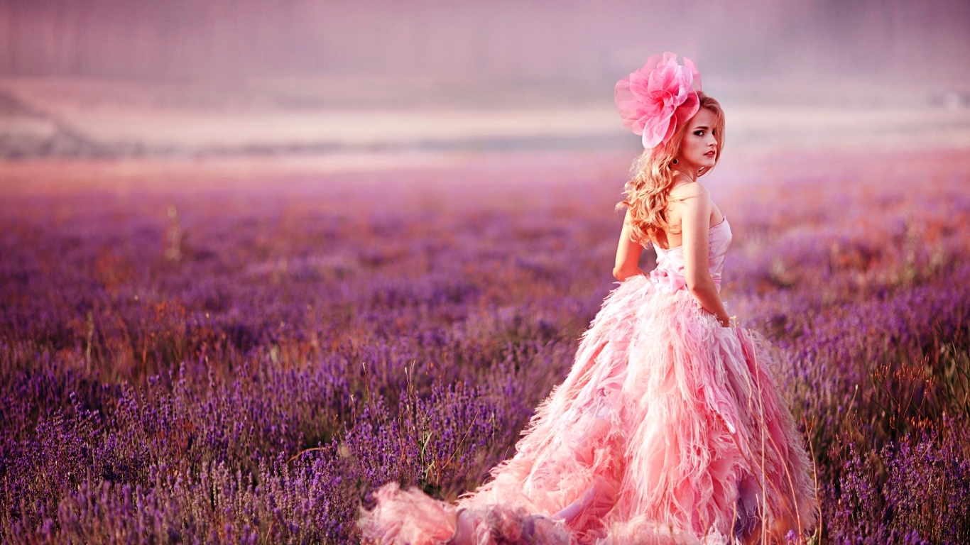 Красивая девушка в розовом платье гуляет по лавандовому полю