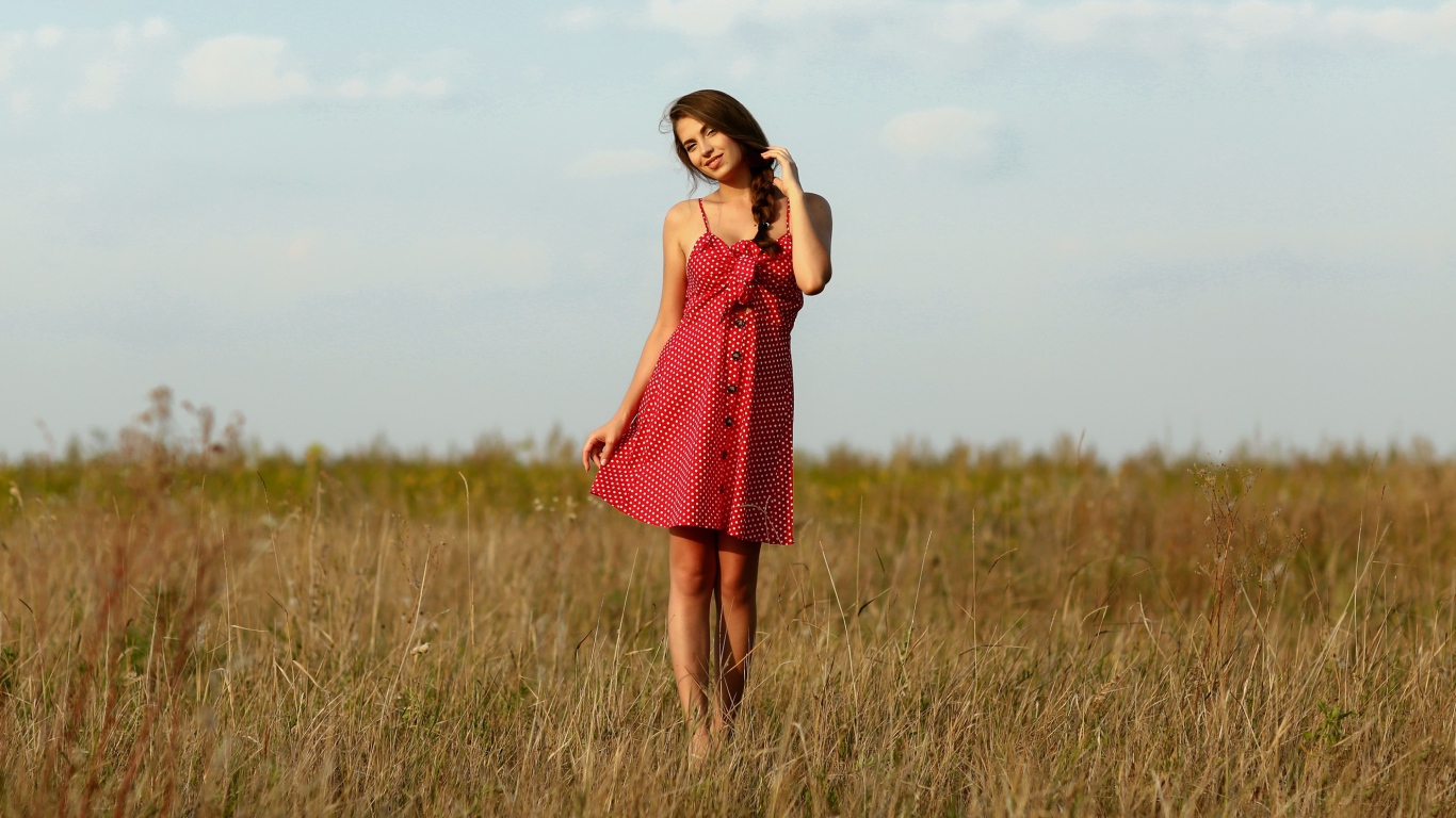 Красивая девушка в красном сарафане на поле 