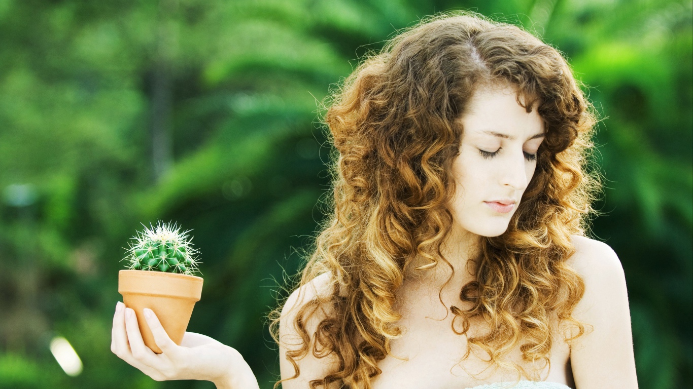 Красивая девушка с закрытыми глазами с кактусом в руке