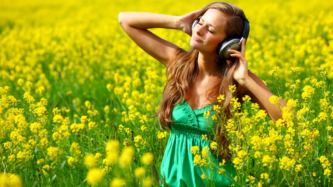 Красивая девушка в наушниках среди желтых цветов