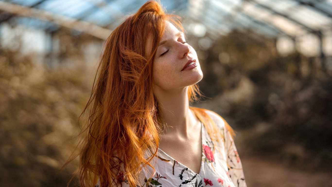 Красивая рыжеволосая девушка нежится в лучах солнца