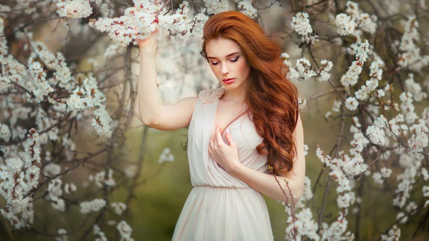 Красивая рыжеволосая девушка у цветущего дерева абрикоса 