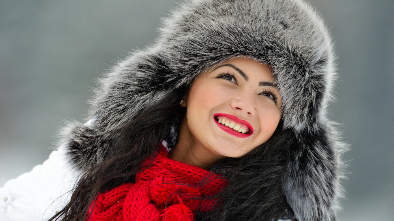 Красивая улыбающаяся брюнетка в теплой зимней шапке