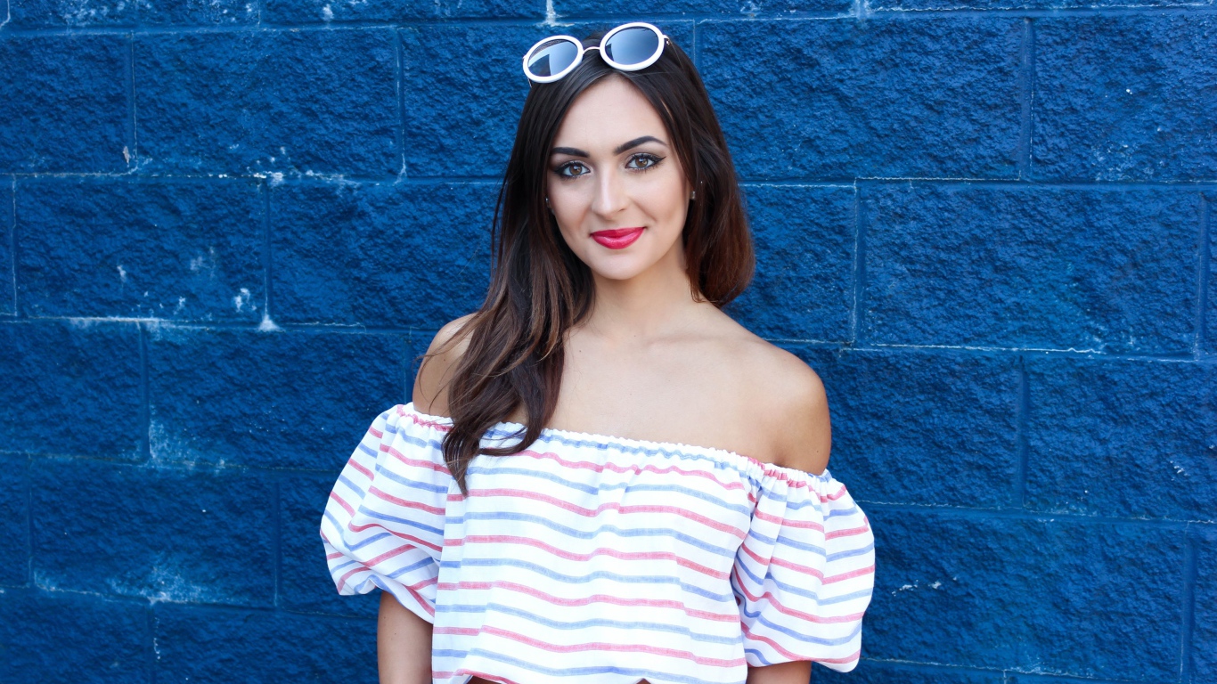 Красивая улыбающаяся девушка на фоне синей стены