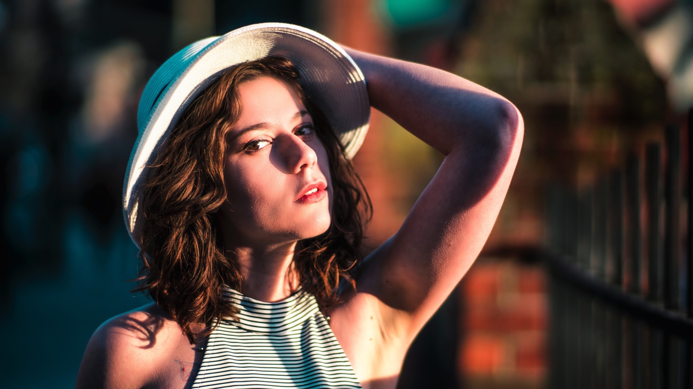 Красивая молодая девушка в белой шляпе в свете солнца