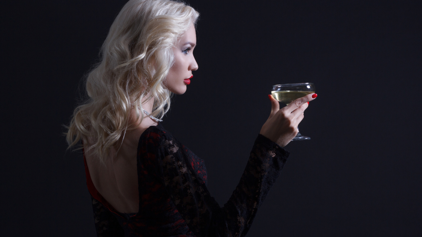 Блондинка с бокалом мартини в руках сером фоне 