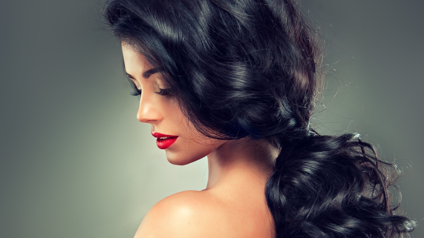 Девушка брюнетка с красивыми волосами на сером фоне