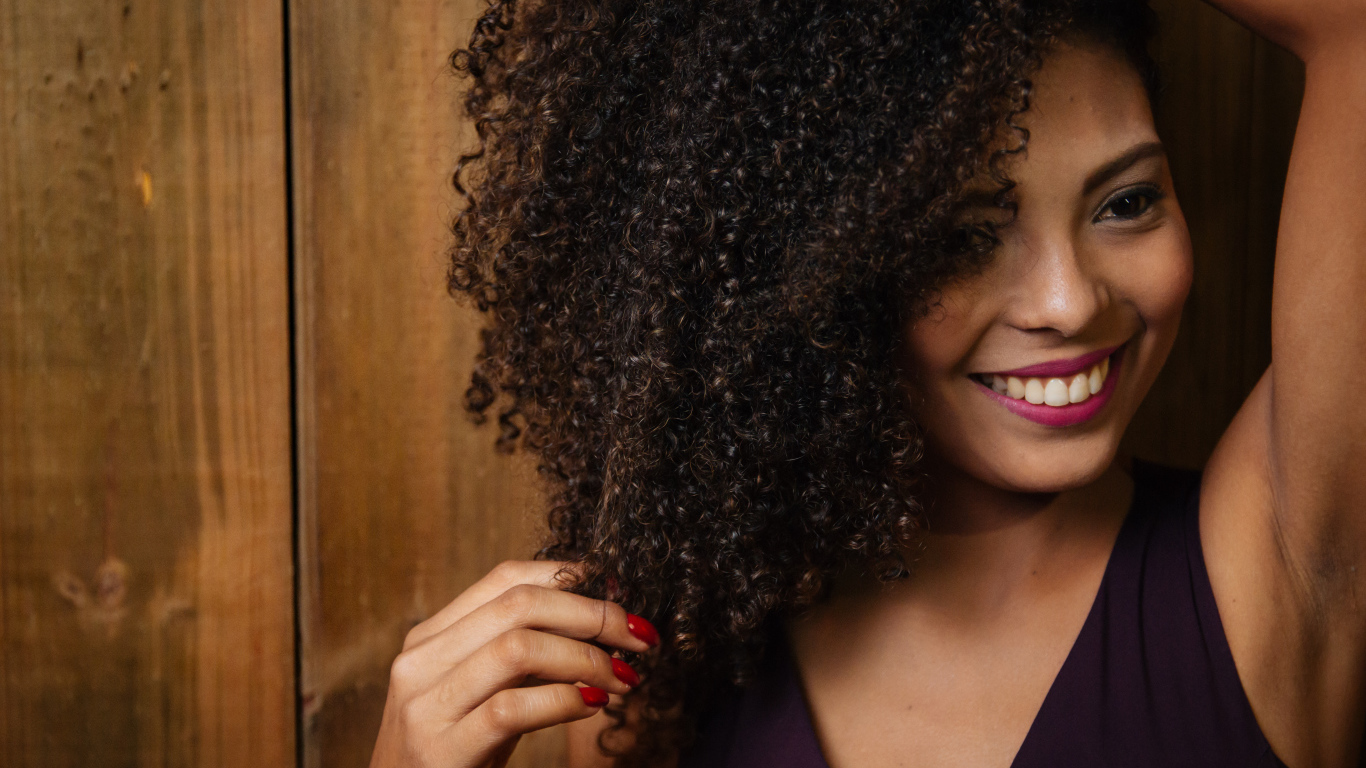 Кучерявая темнокожая девушка с красивой улыбкой 