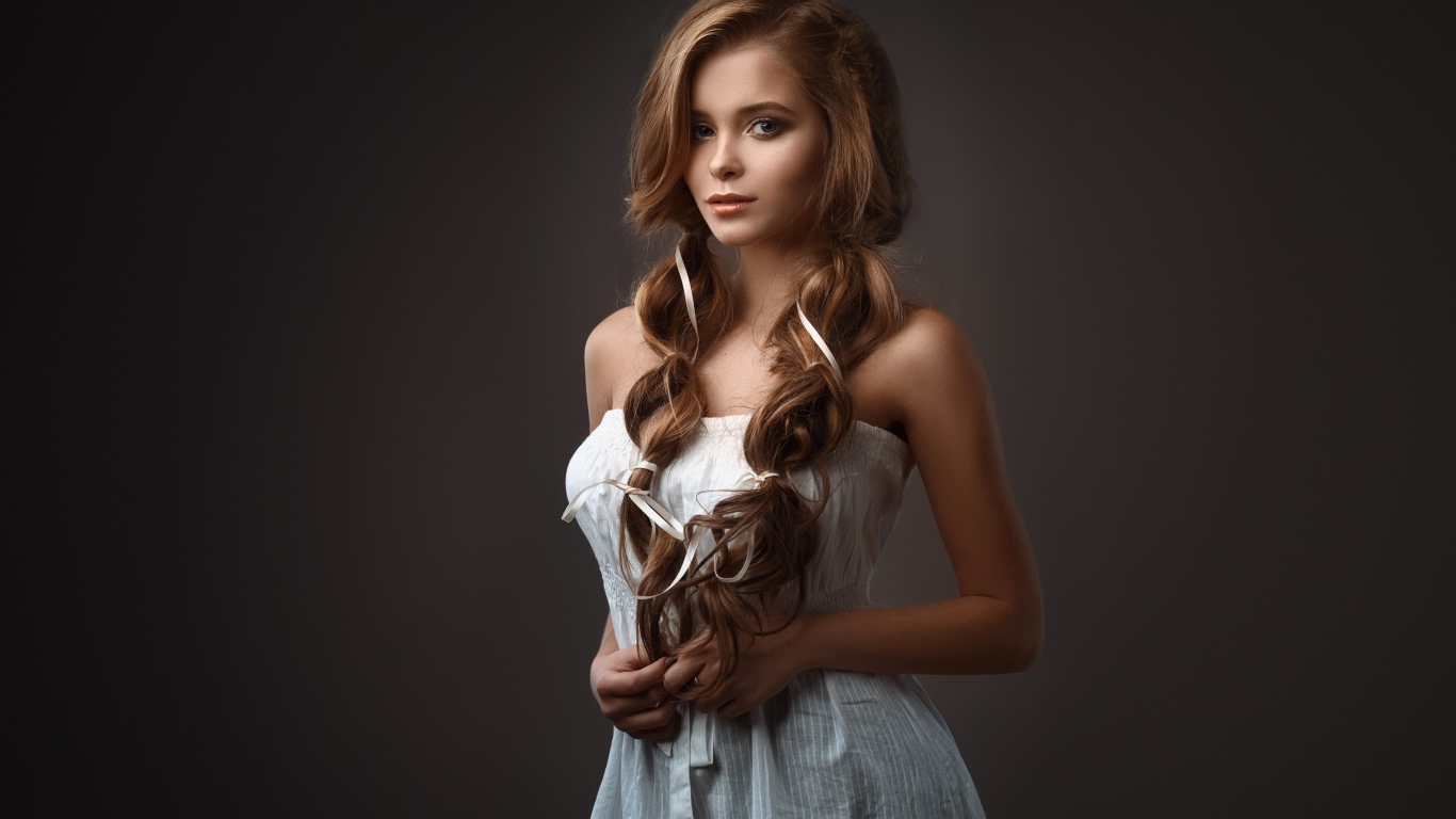 Нежная длинноволосая девушка на сером фоне