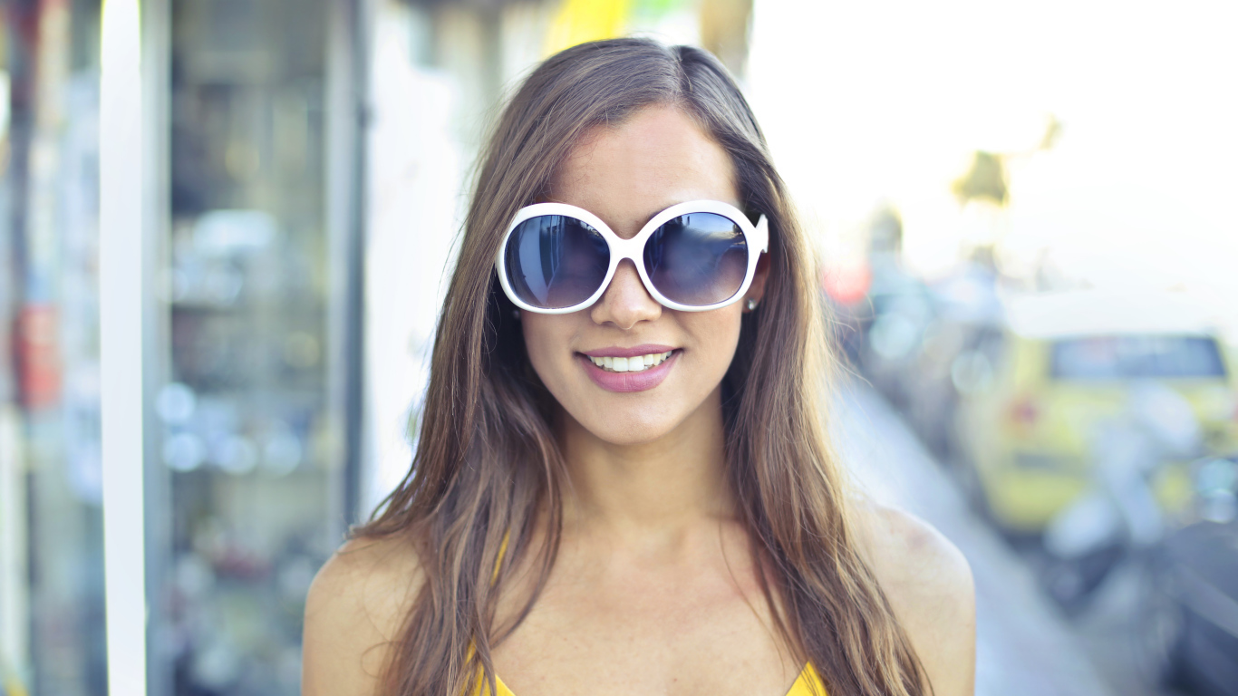 Улыбающаяся молодая девушка в солнечных очках 