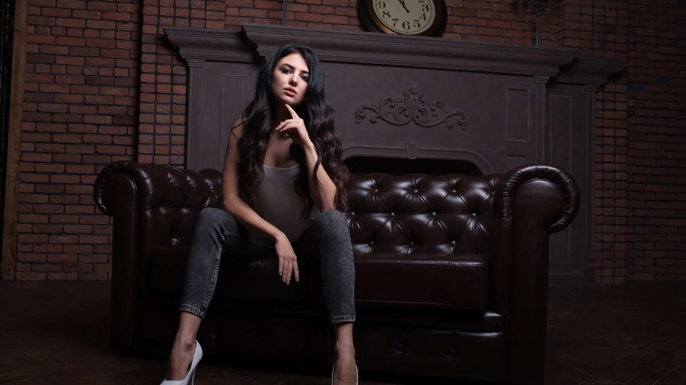 Стильная девушка сидит на кожаном диване