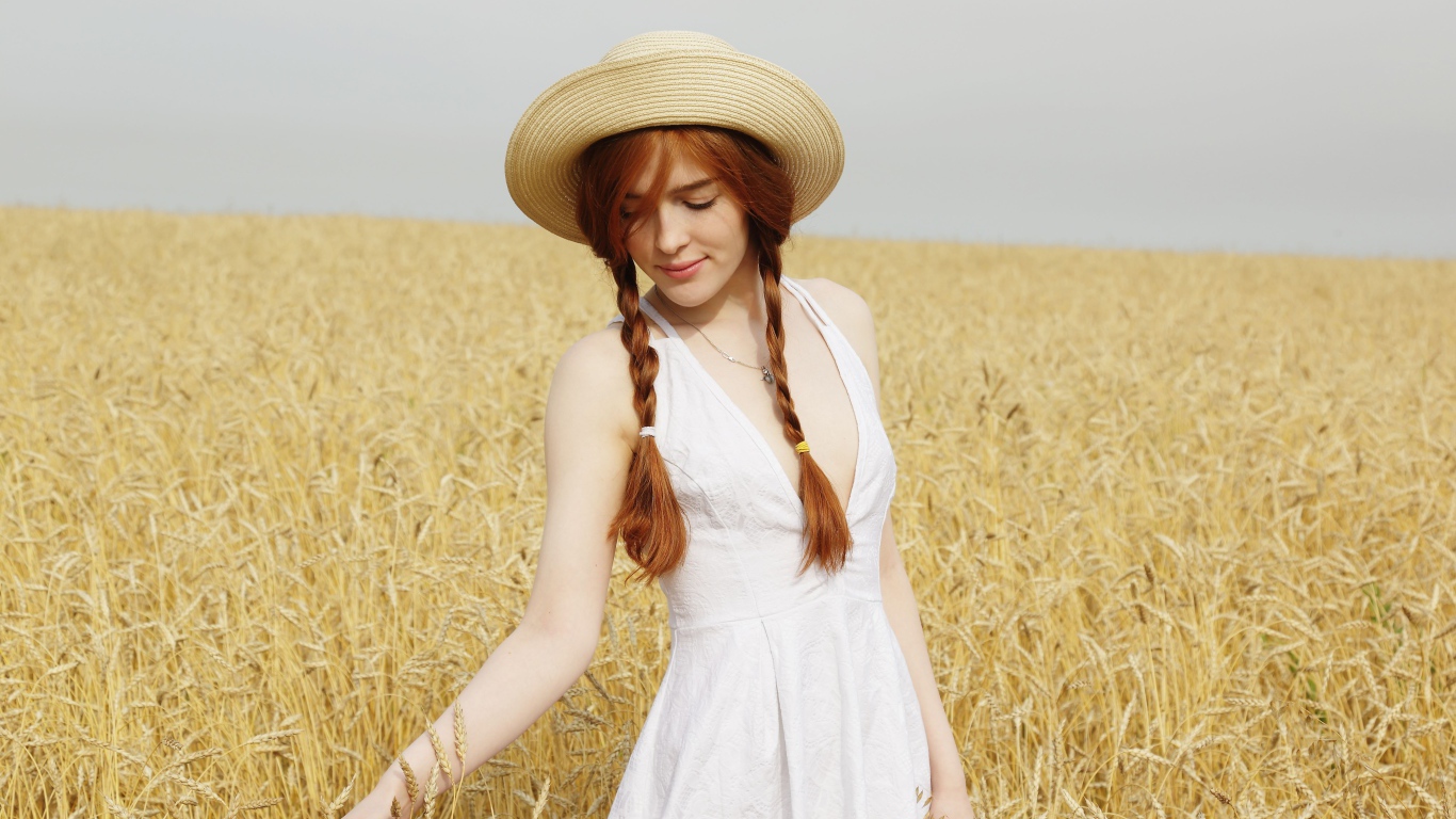 Молодая девушка в белом платье на поле с пшеницей