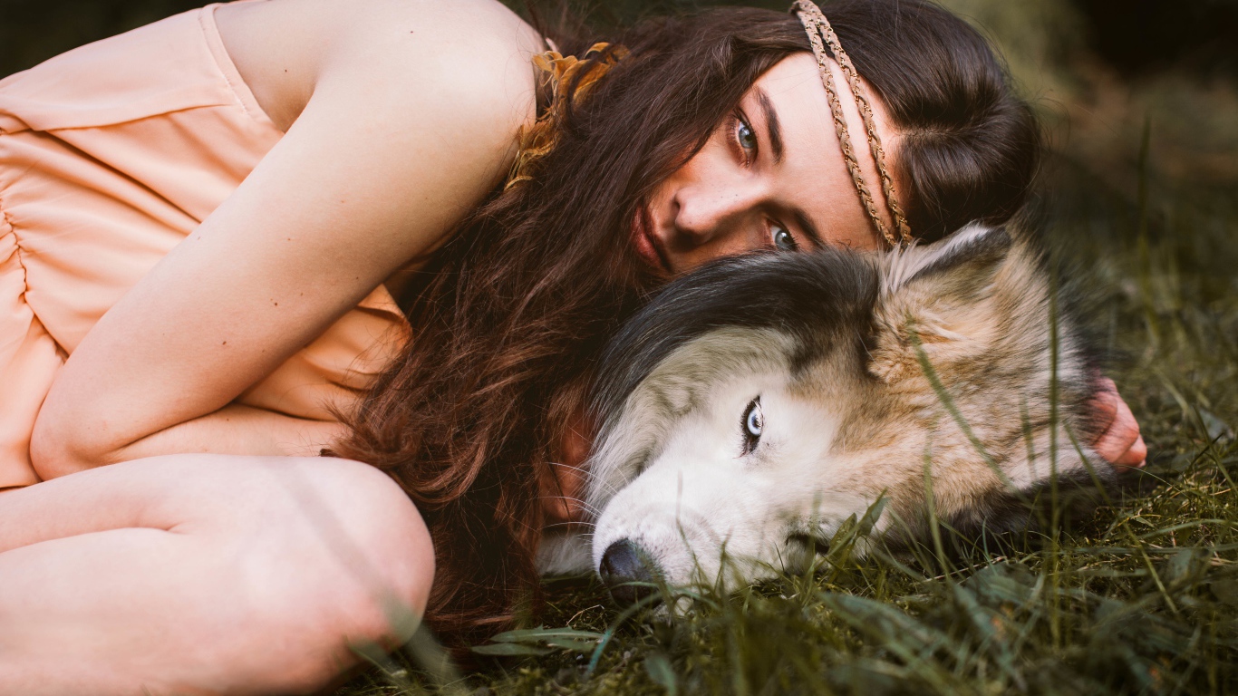 Молодая девушка с собакой породы хаски лежит на траве