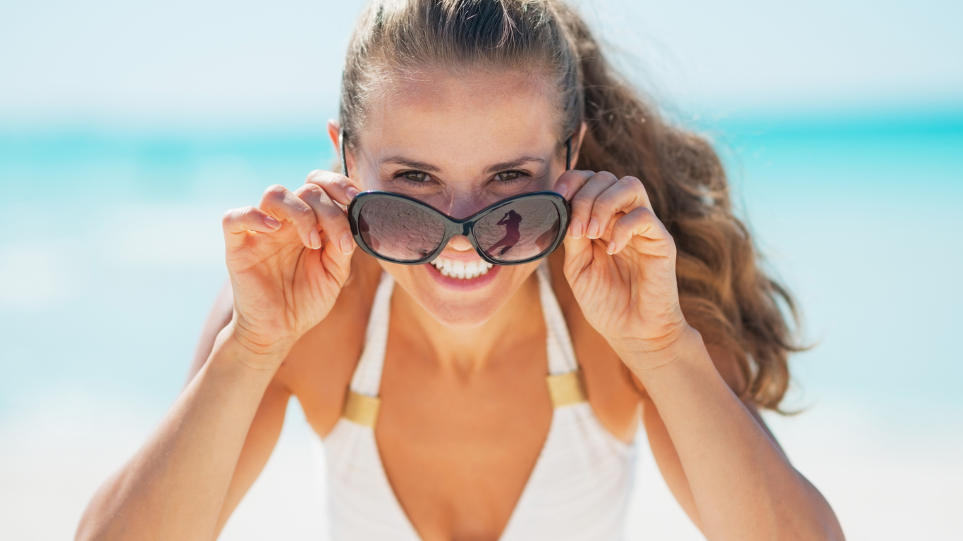Молодая улыбающаяся девушка в солнечных очках 