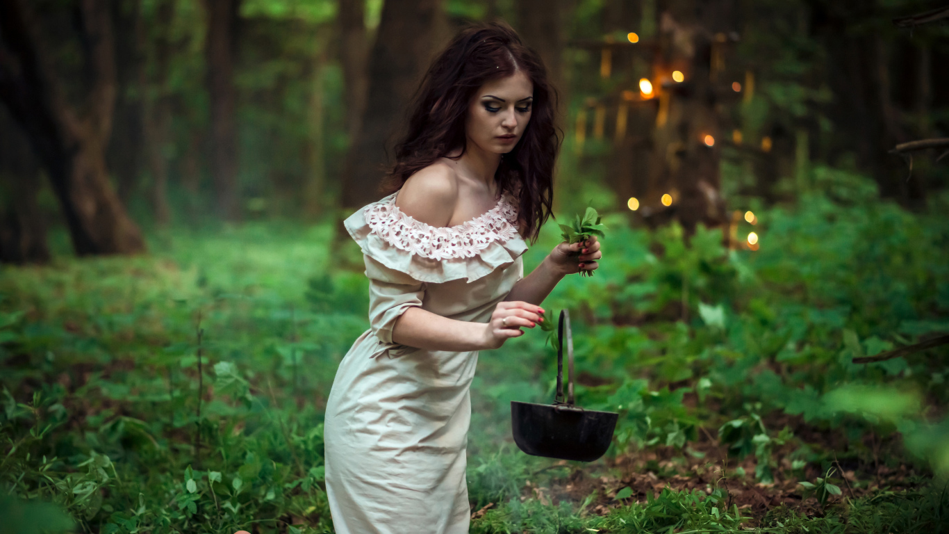 Молодая девушка колдунья варит зелье в лесу