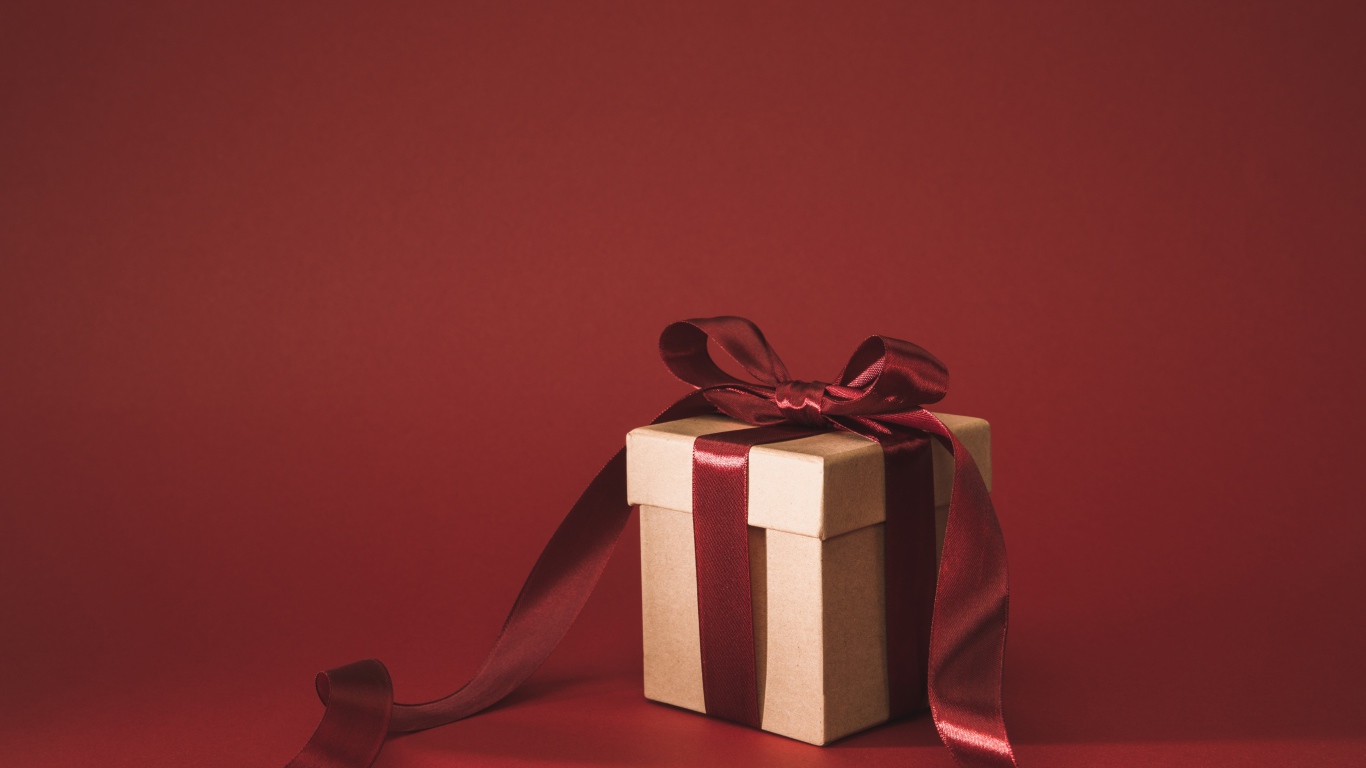 Подарочная коробка с красным бантом на красном фоне