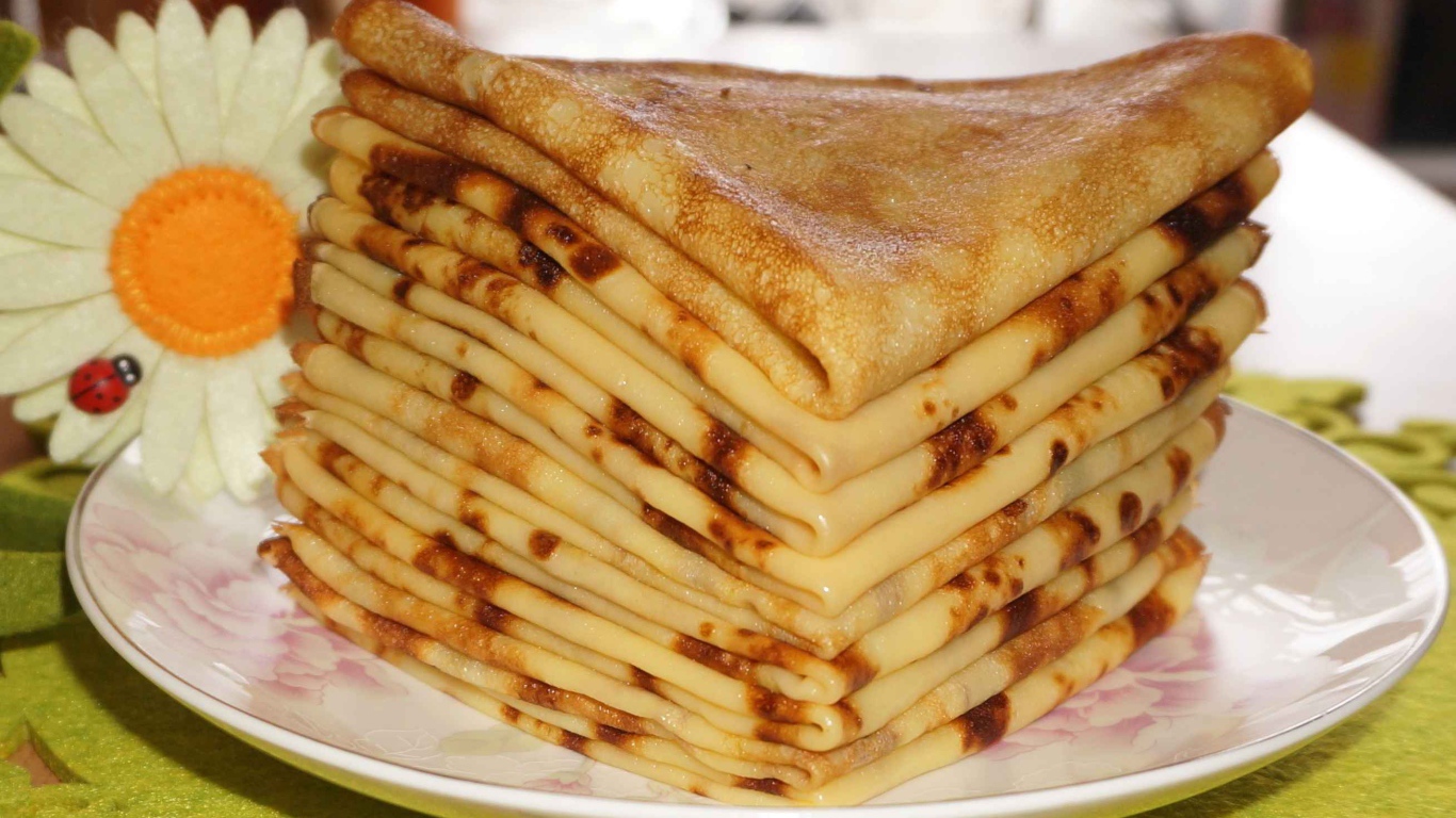 Стопка тонких блинов с ромашкой на Масленицу