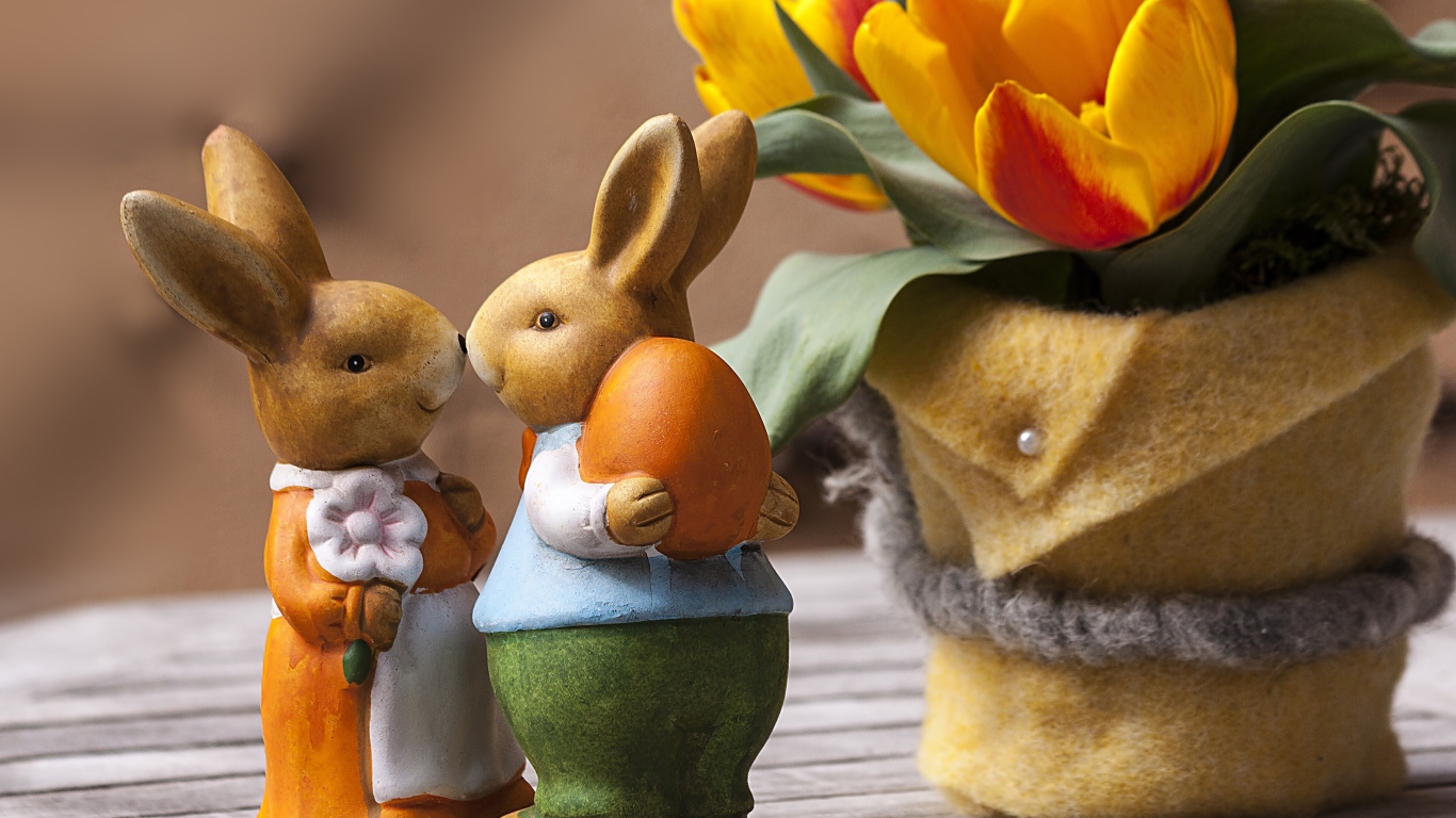 Статуэтки пасхальных кроликов на столе с тюльпанами