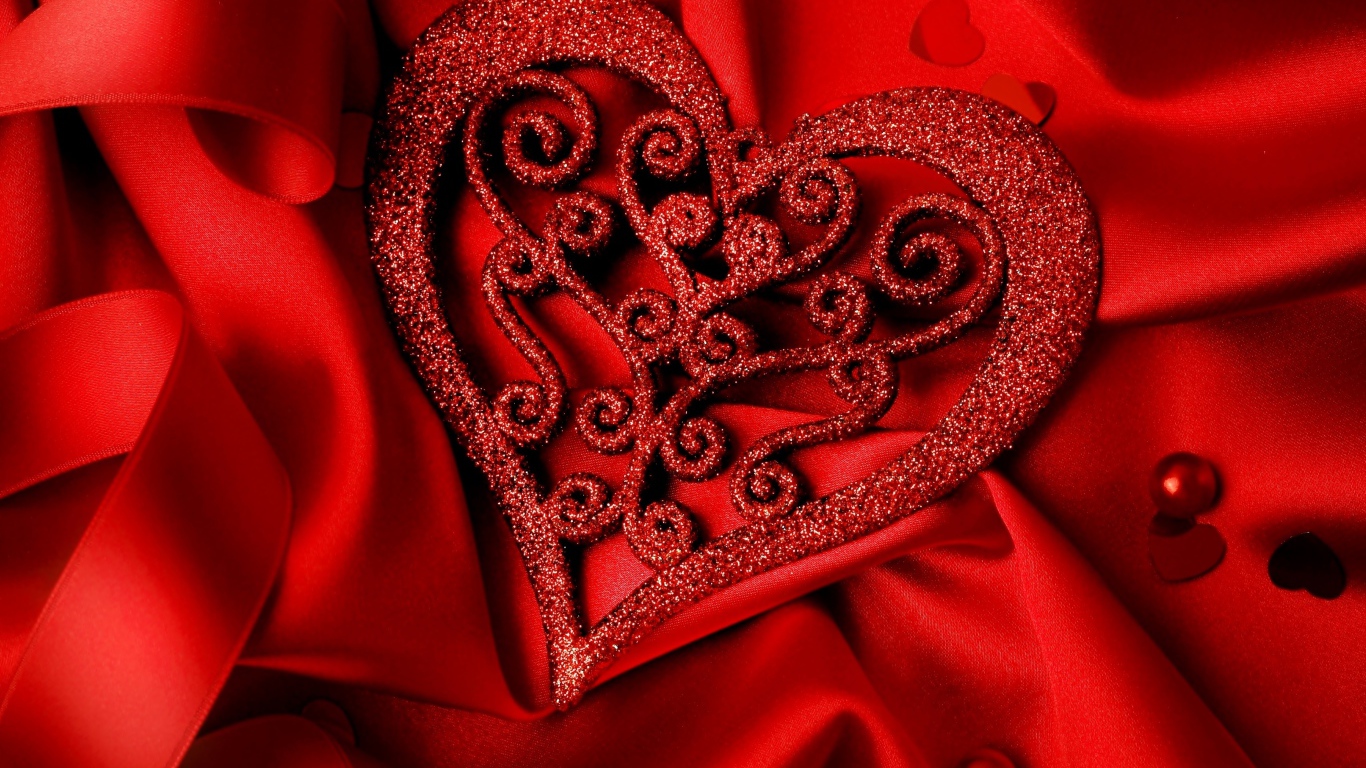 Блестящее сердце на красной атласной ткани 