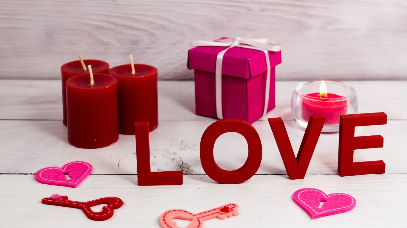 Надпись любовь на столе с красными свечами и подарком