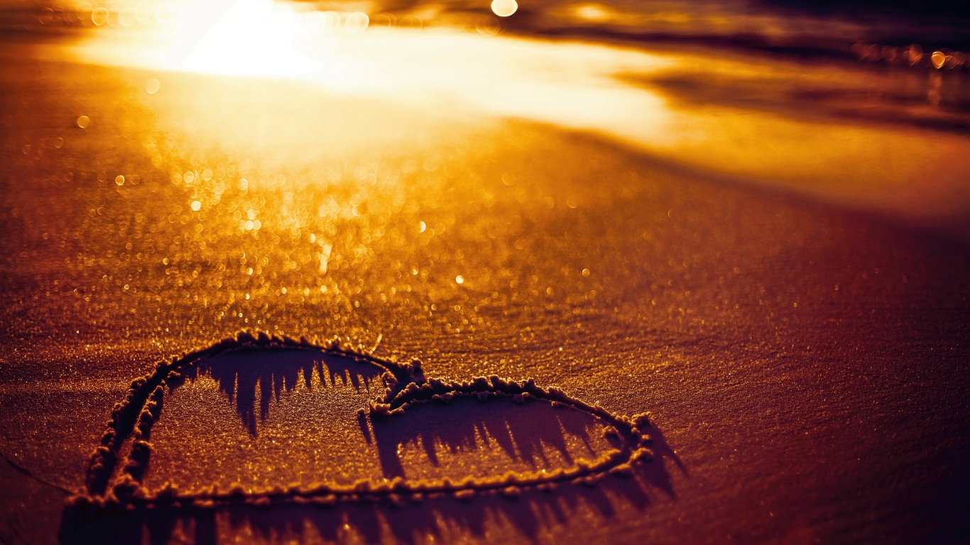 Нарисованное сердце на песке в лучах солнца