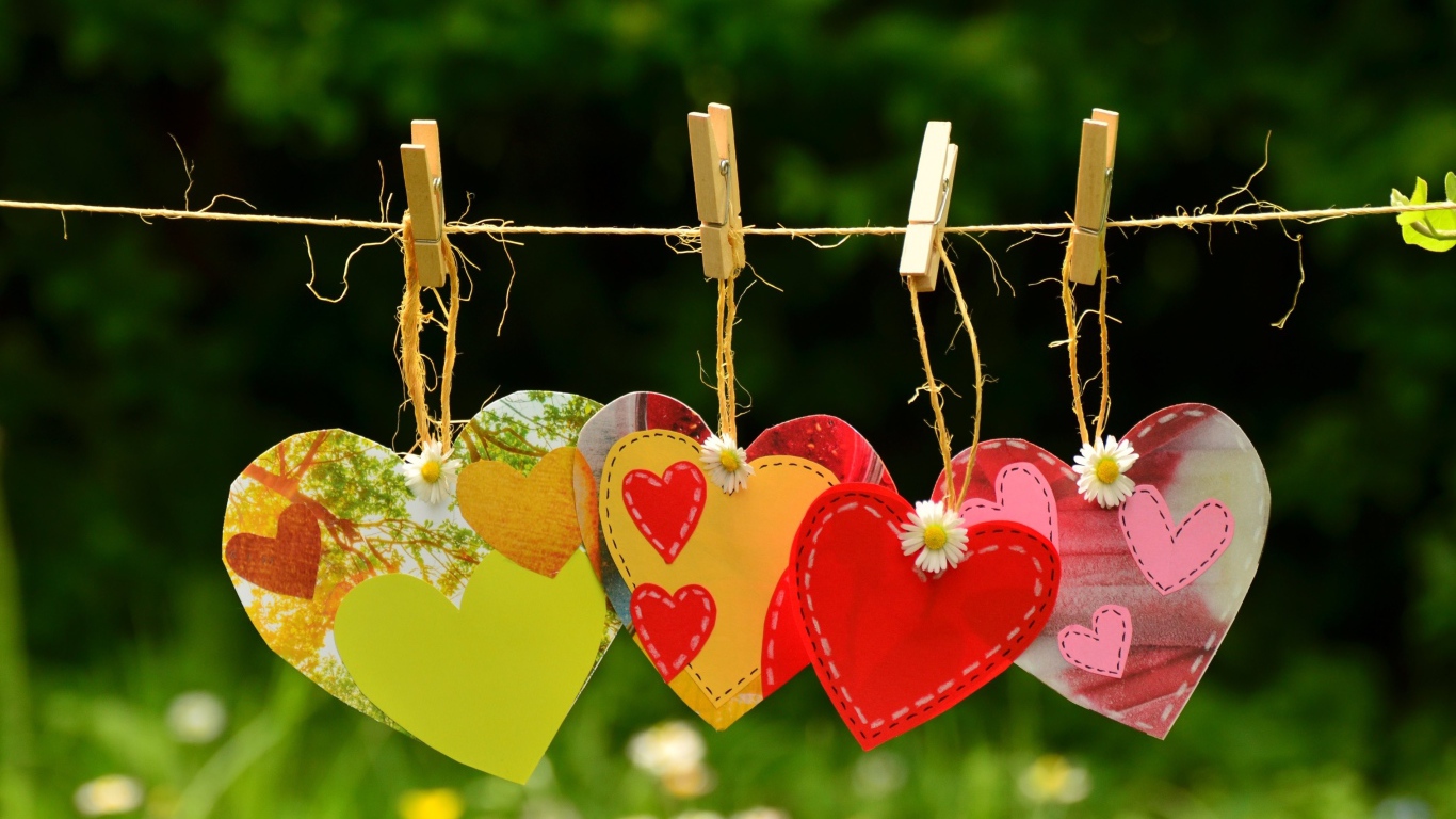 Бумажные сердечки висят на веревке на прищепках