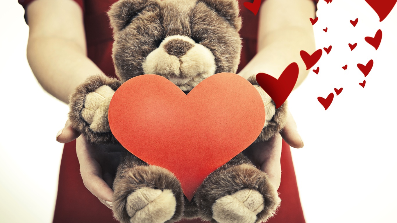 Плюшевый медведь с большим красным сердцем в руках