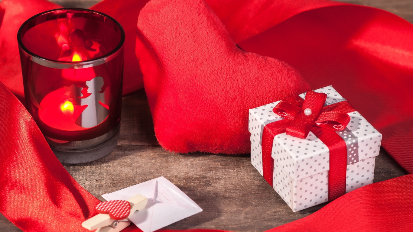 Мягкое красное сердце на столе с подарком и зажженной свечей