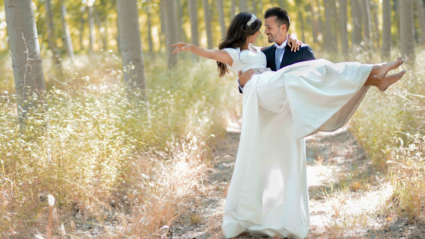 Парень жених держит на руках невесту в белом платье