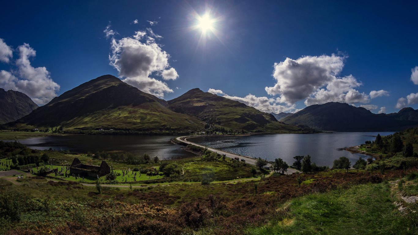 Яркое солнце в голубом небе над горами у реки