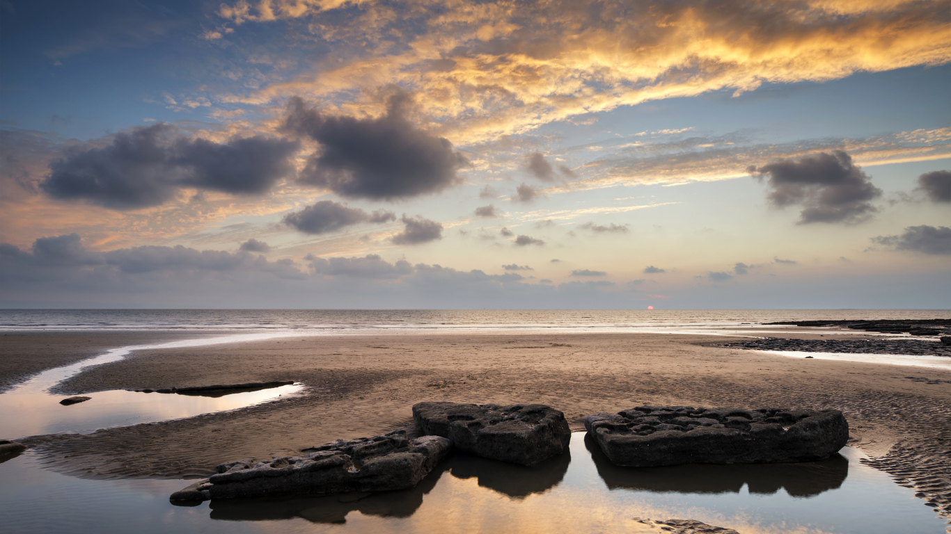 Большие камни в воде на песке под красивым небом