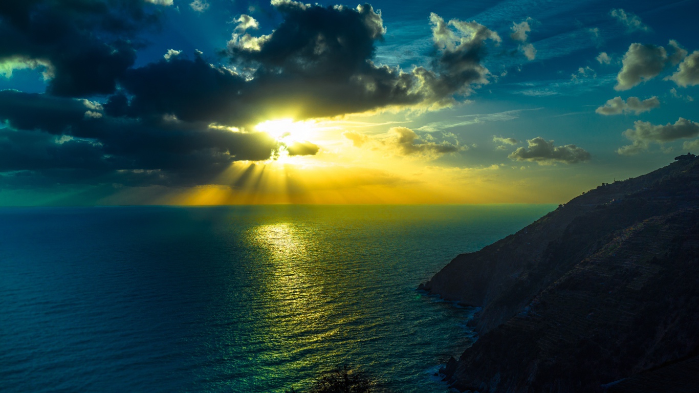 Лучи яркого солнца пробиваются сквозь облака над морем