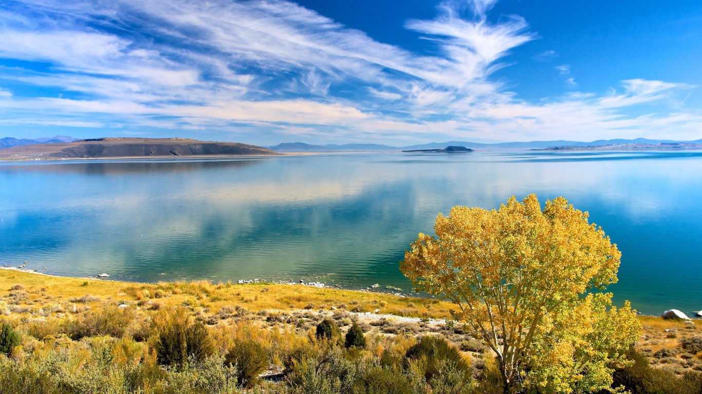 Белые облака в голубом небе отражаются в озере