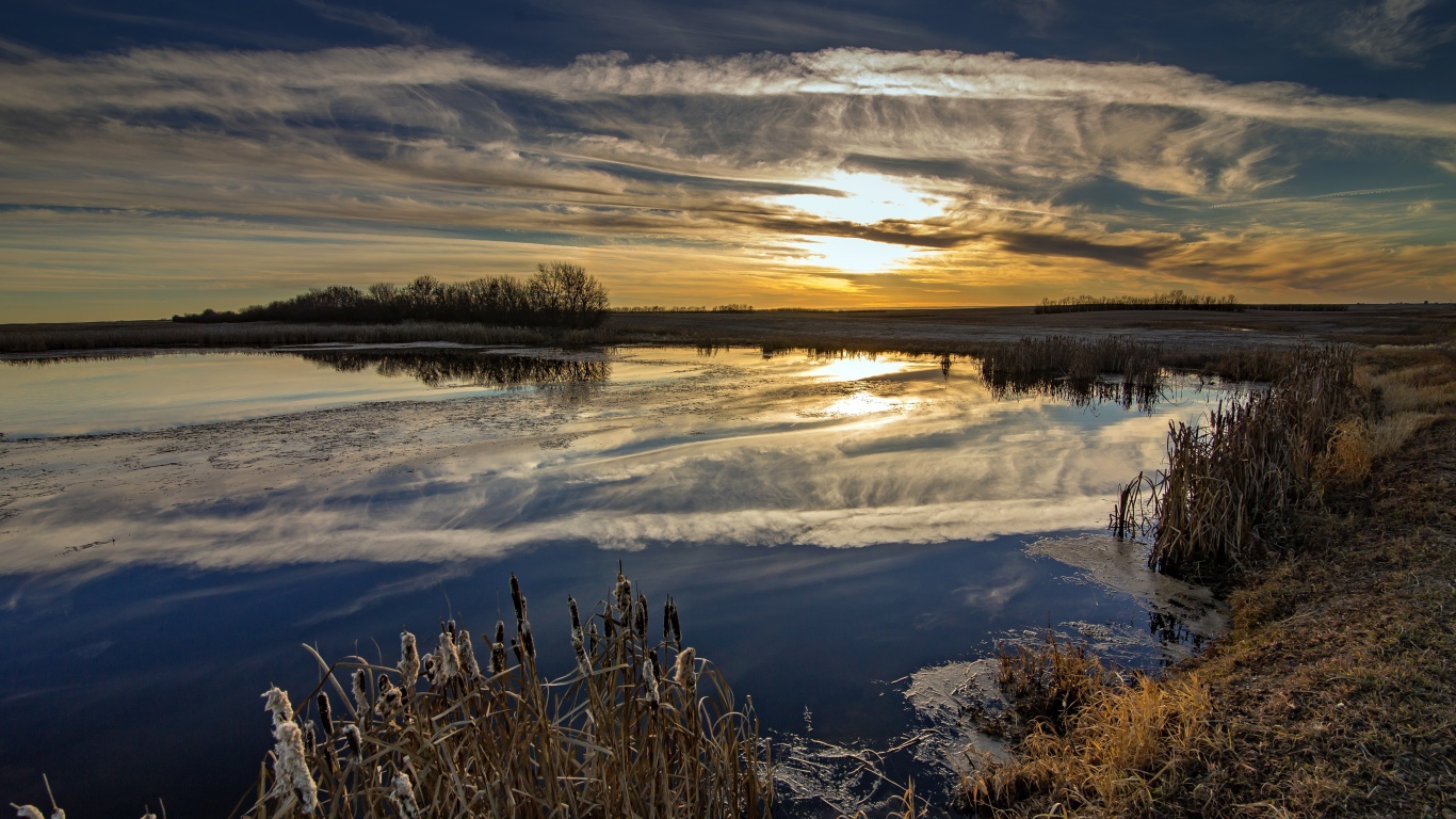 Белые облака отражаются в воде на закате солнца