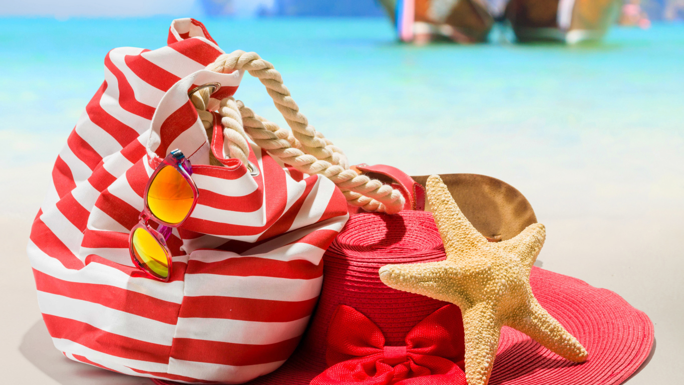 Большая красная шляпа с сумкой и морской звездой на пляже