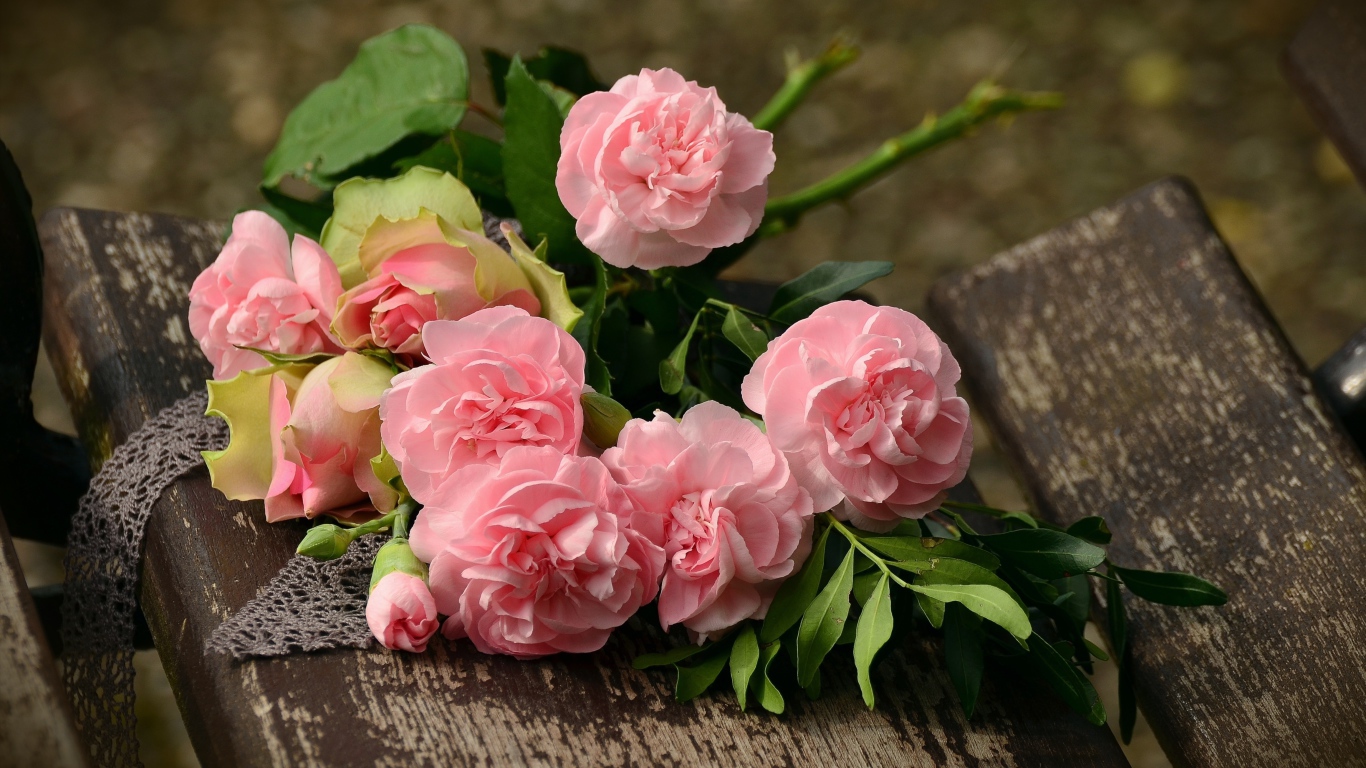 Букет красивых нежных розовых роз лежит на деревянной лавке