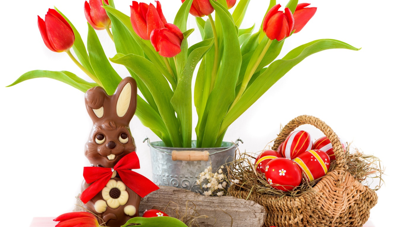 Букет красных тюльпанов на столе с шоколадным кроликом и крашеными яйцами на Пасху
