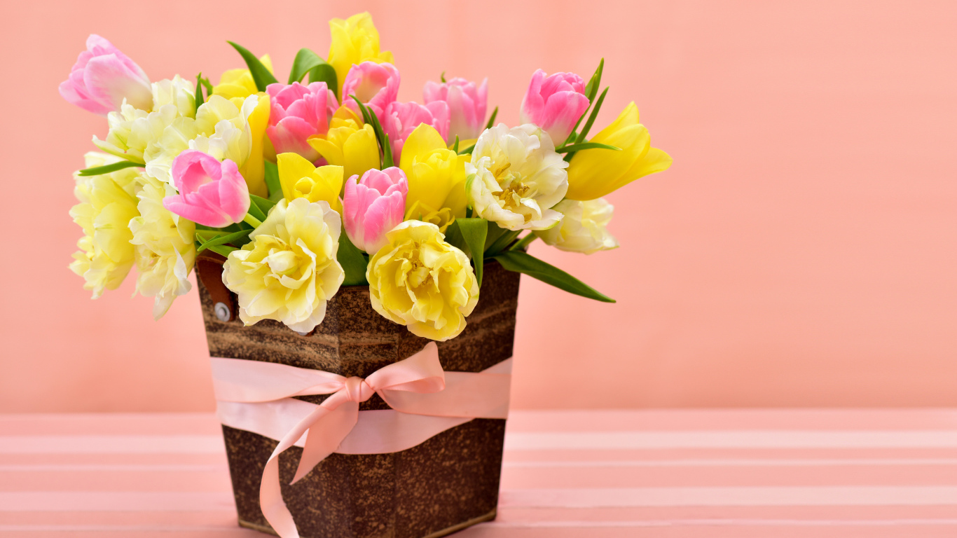Bouquet of beautiful multicolored tulips in a vase on a pink background