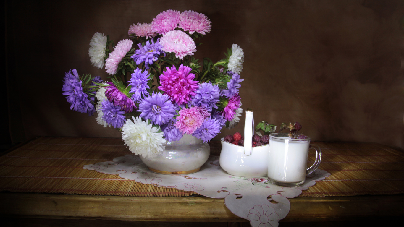 Букет разноцветных астр в вазе на столе с молоком и ягодами малины