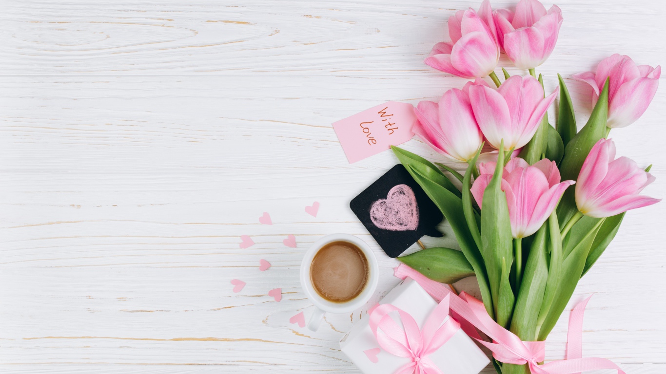 Букет розовых тюльпанов на столе с чашкой кофе и подарком 