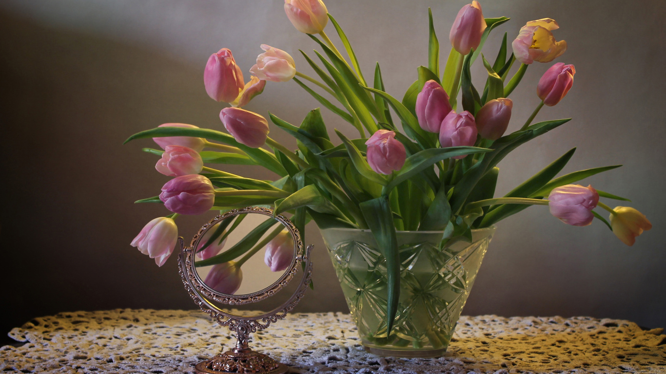 Розовые тюльпаны в стеклянной вазе на столе с зеркалом 