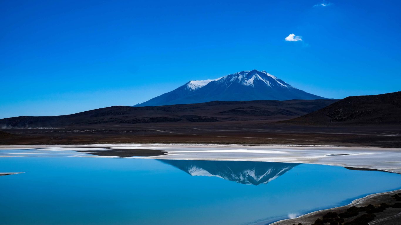 Гора отражается в воде на фоне голубого неба