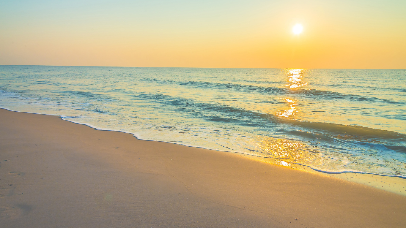 Морские волны на желтом песке на закате солнца летом