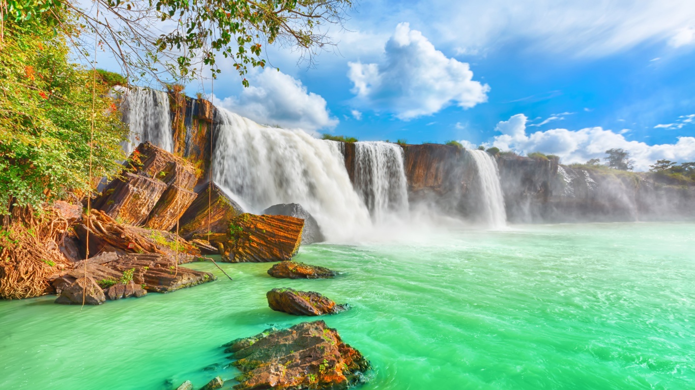 Быстрый водопад стекает со скалы под красивым голубым небом