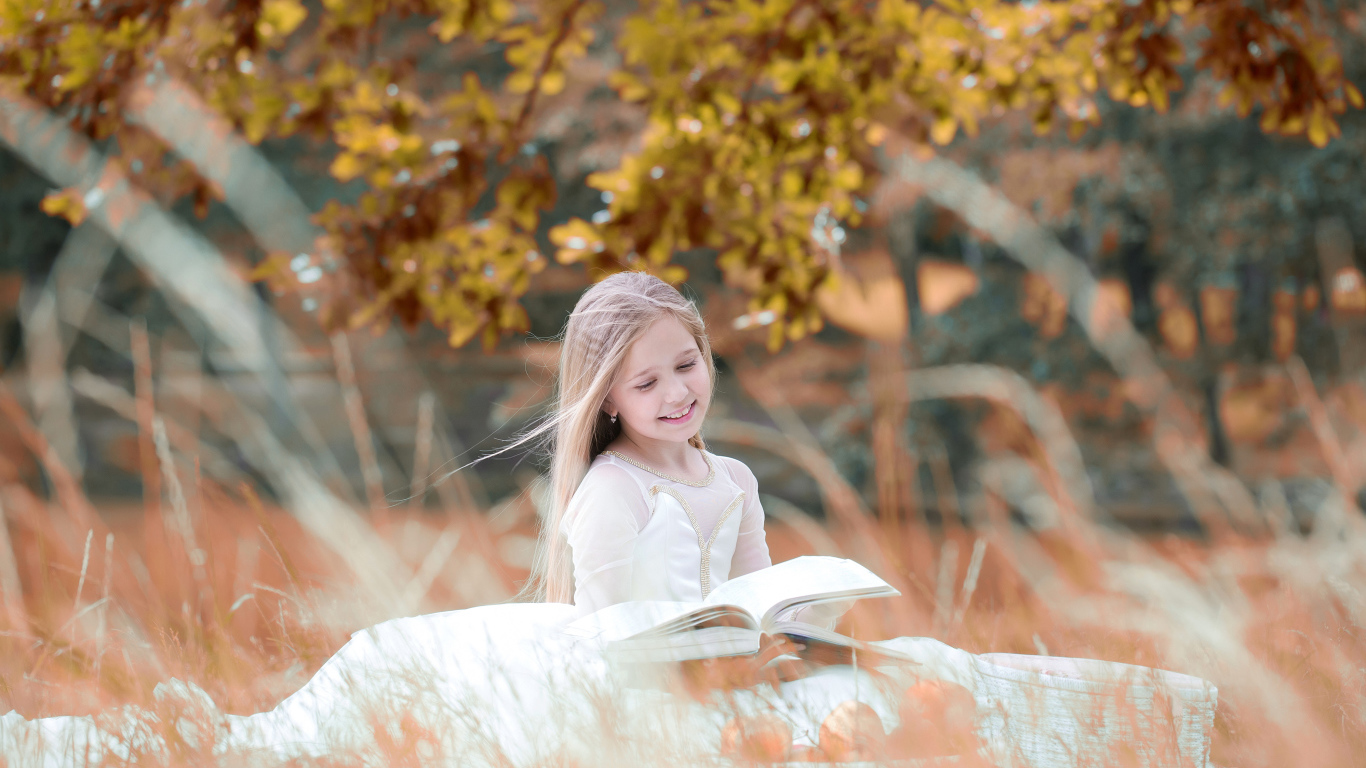 Девочка в красивом белом платье читает книгу на природе