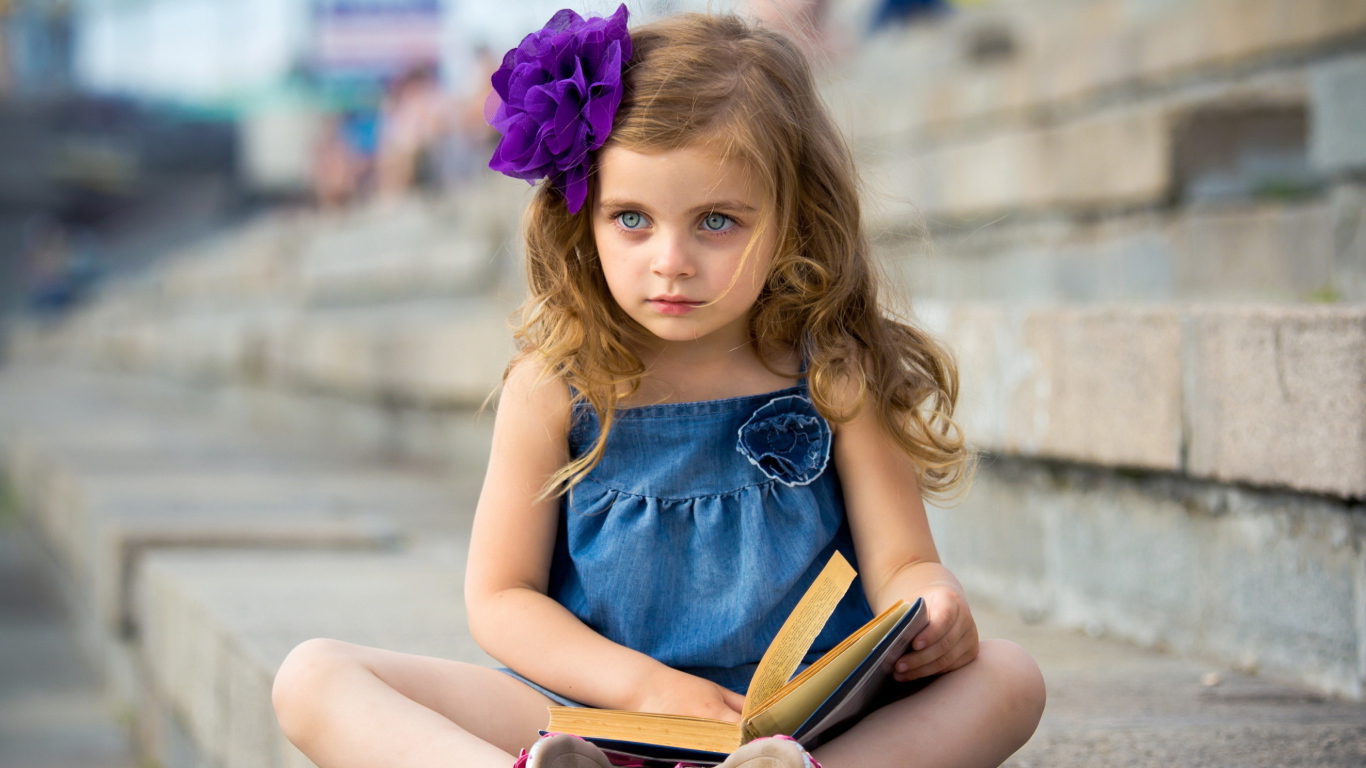 Маленькая девочка с цветком в волосах сидит на ступенях