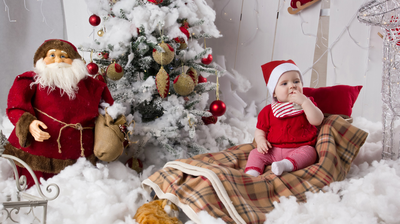 Маленький ребенок в санях у елки с дедом морозом на Новый год 