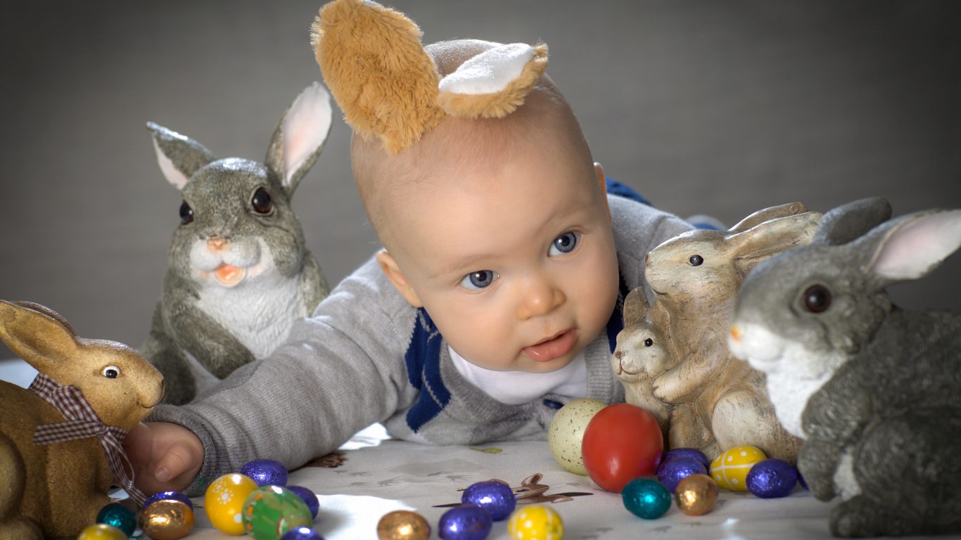 Маленький ребенок с пасхальными кроликами и яйцами