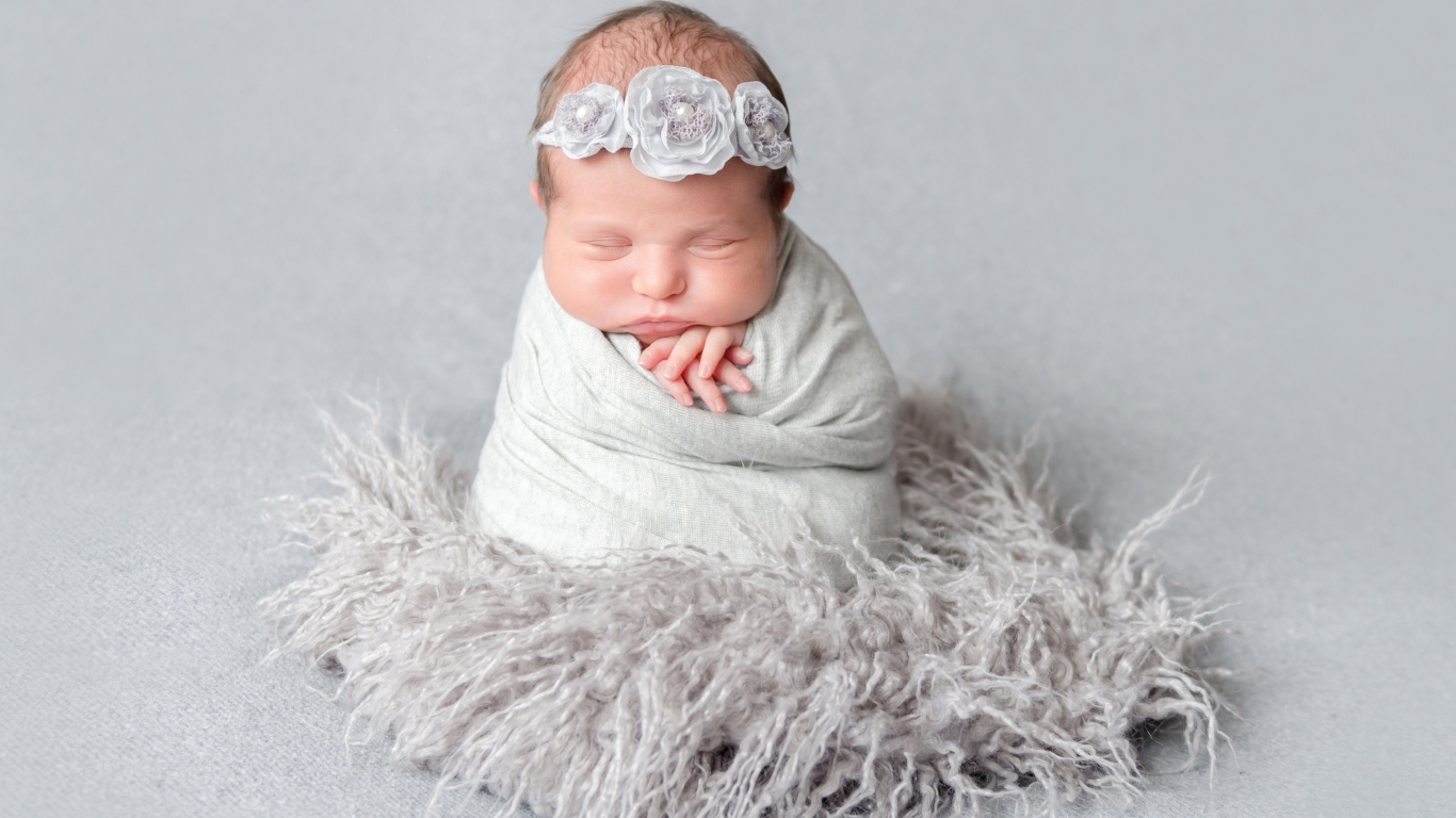 Маленький спящий младенец на сером фоне