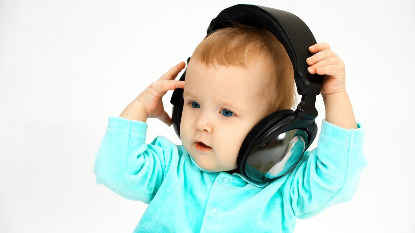 Голубоглазый мальчик в больших наушниках на белом фоне